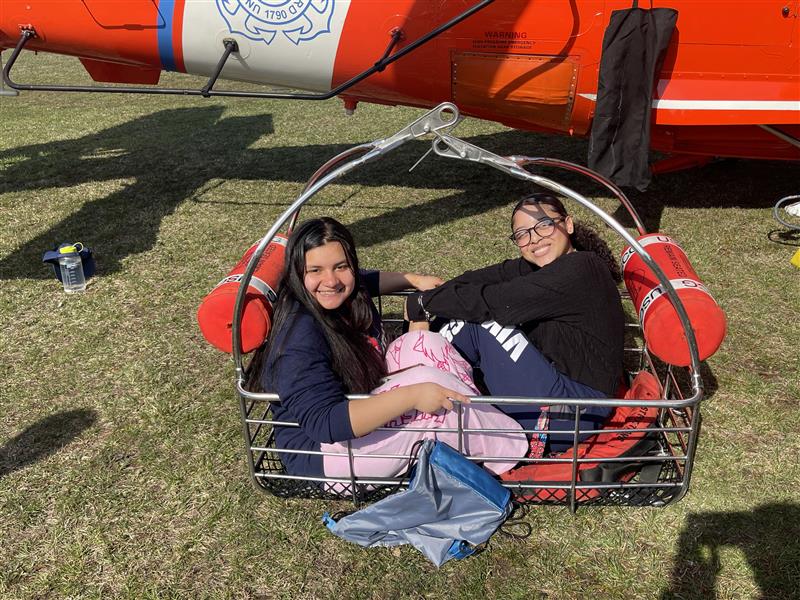 Samantha Cabrera and Kimberly Guzman-Chirinos sit in a Coast Guard rescue basket.